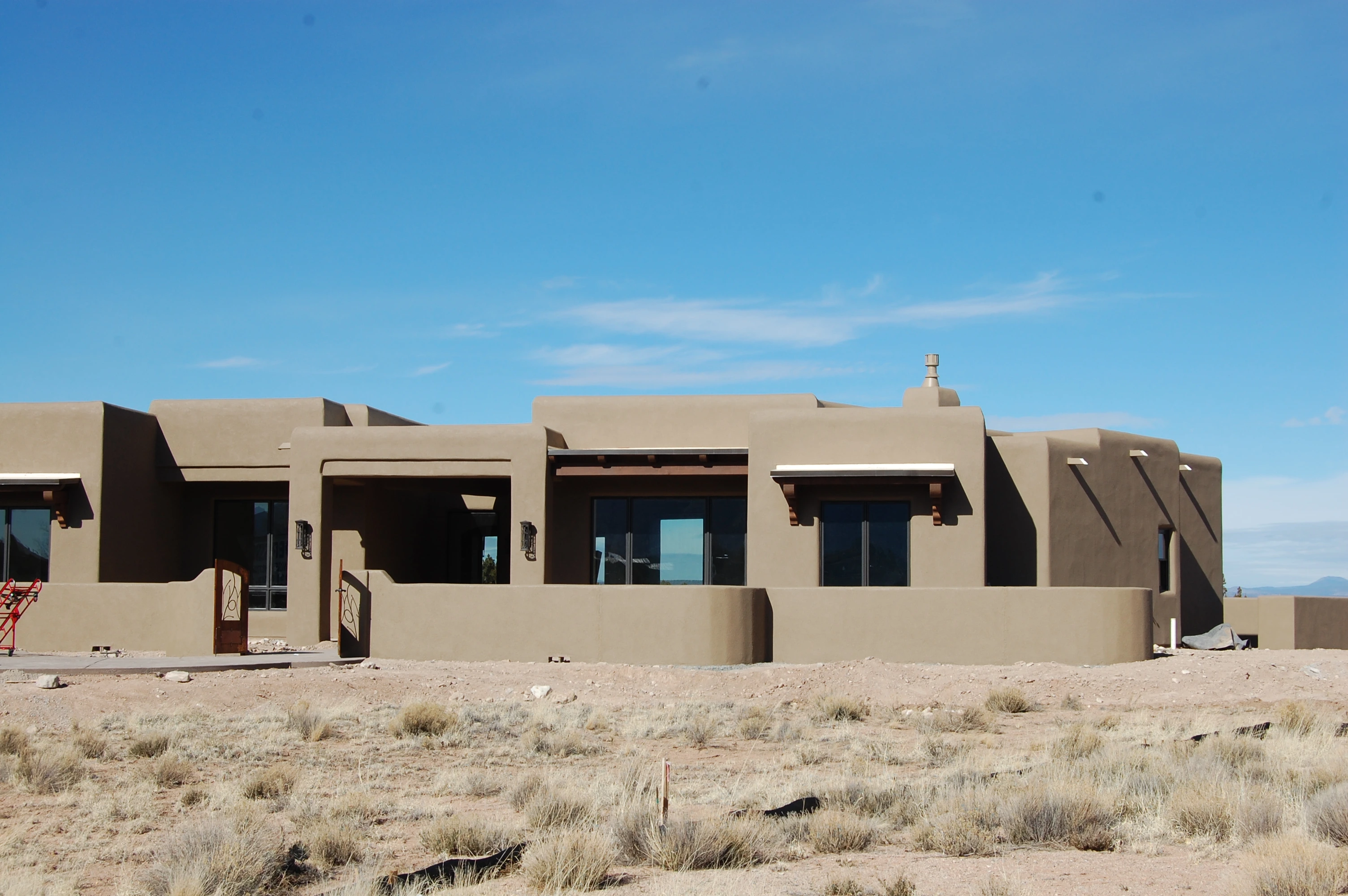 An expansive adobe-style residence with stunning mountains rising in the background, highlighting the beauty of the landscape.